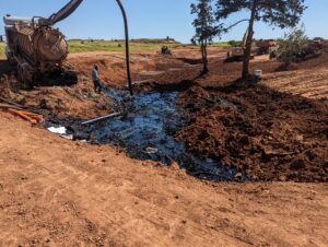 Vacuum truck removing oily sludge from a ditch