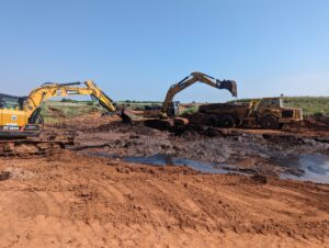 Excavators and dump trucks removing and hauling off contaminated soil to a disposal site