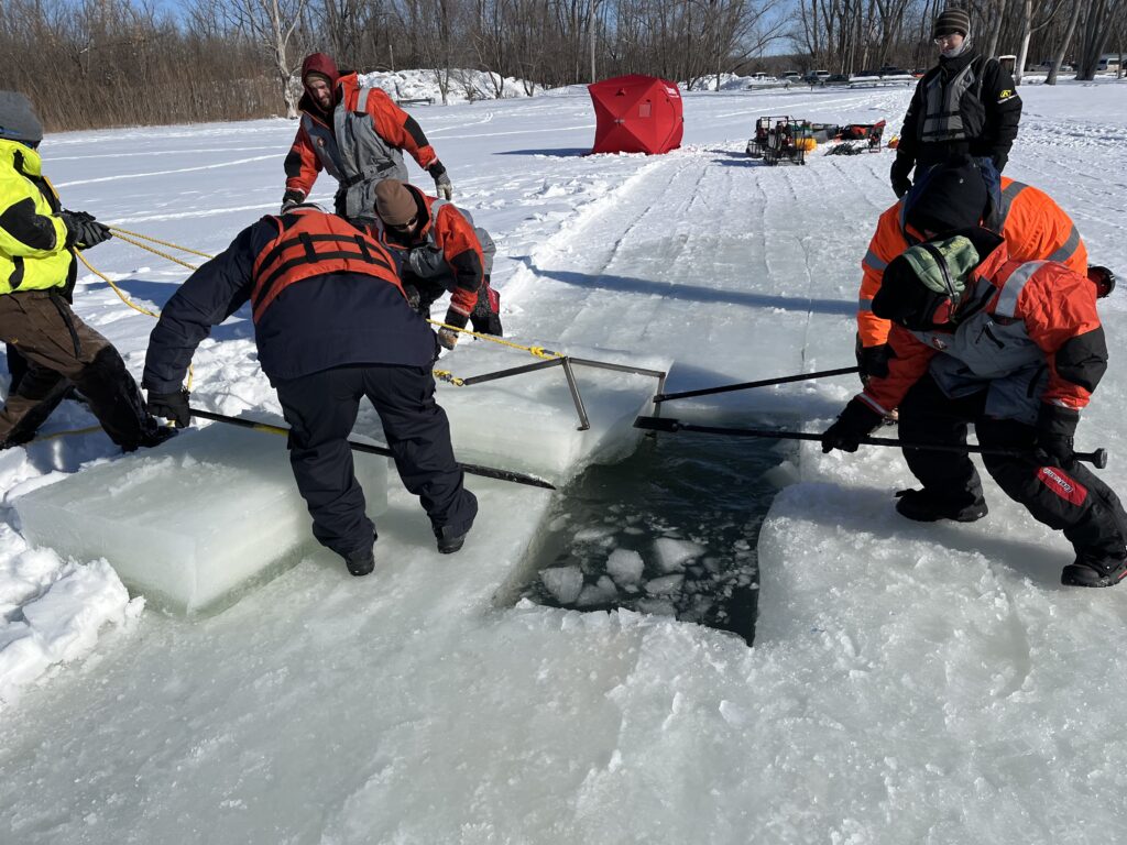Response team removing ice to expose water for the containment solution to be deployed
