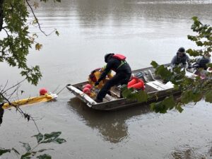 Participants Attaching Containment Boom to Boat to be Pulled Out Into Water for Deployment